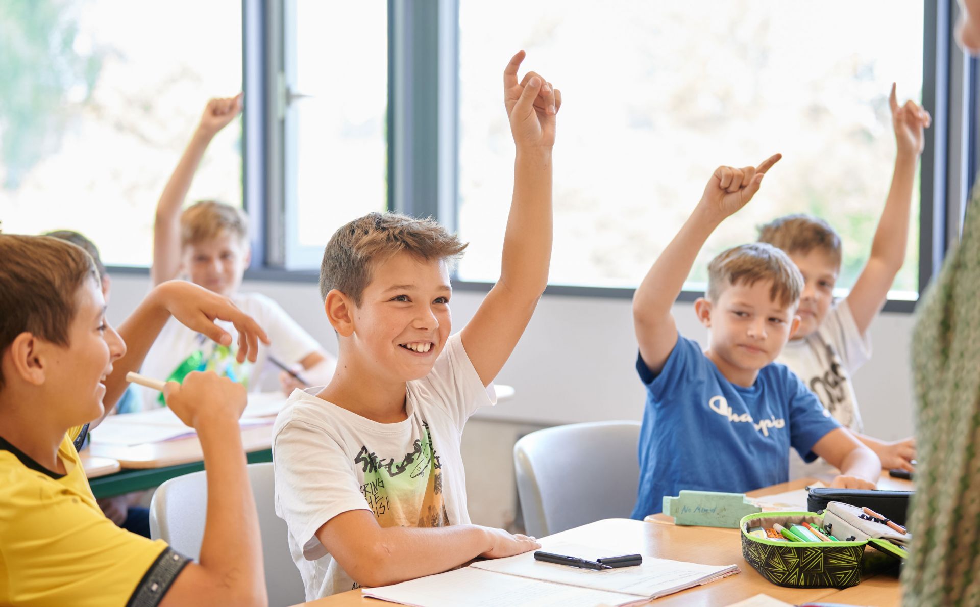 Mehrere junge Schüler strecken im Unterricht. 