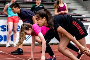 Mehrere Schüler in der Startposition zum Sprint auf der Tartanbahn